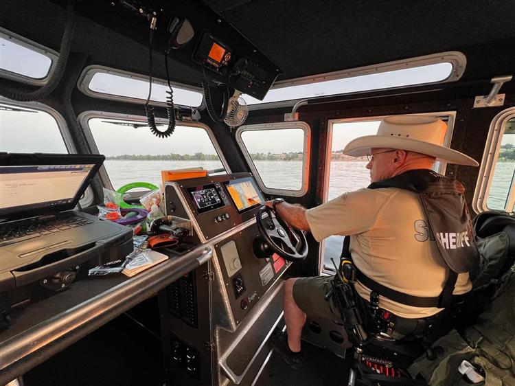 law enforcement officer, likely from the Pinellas County Sheriff's Office Marine Unit, at the helm of a patrol boat